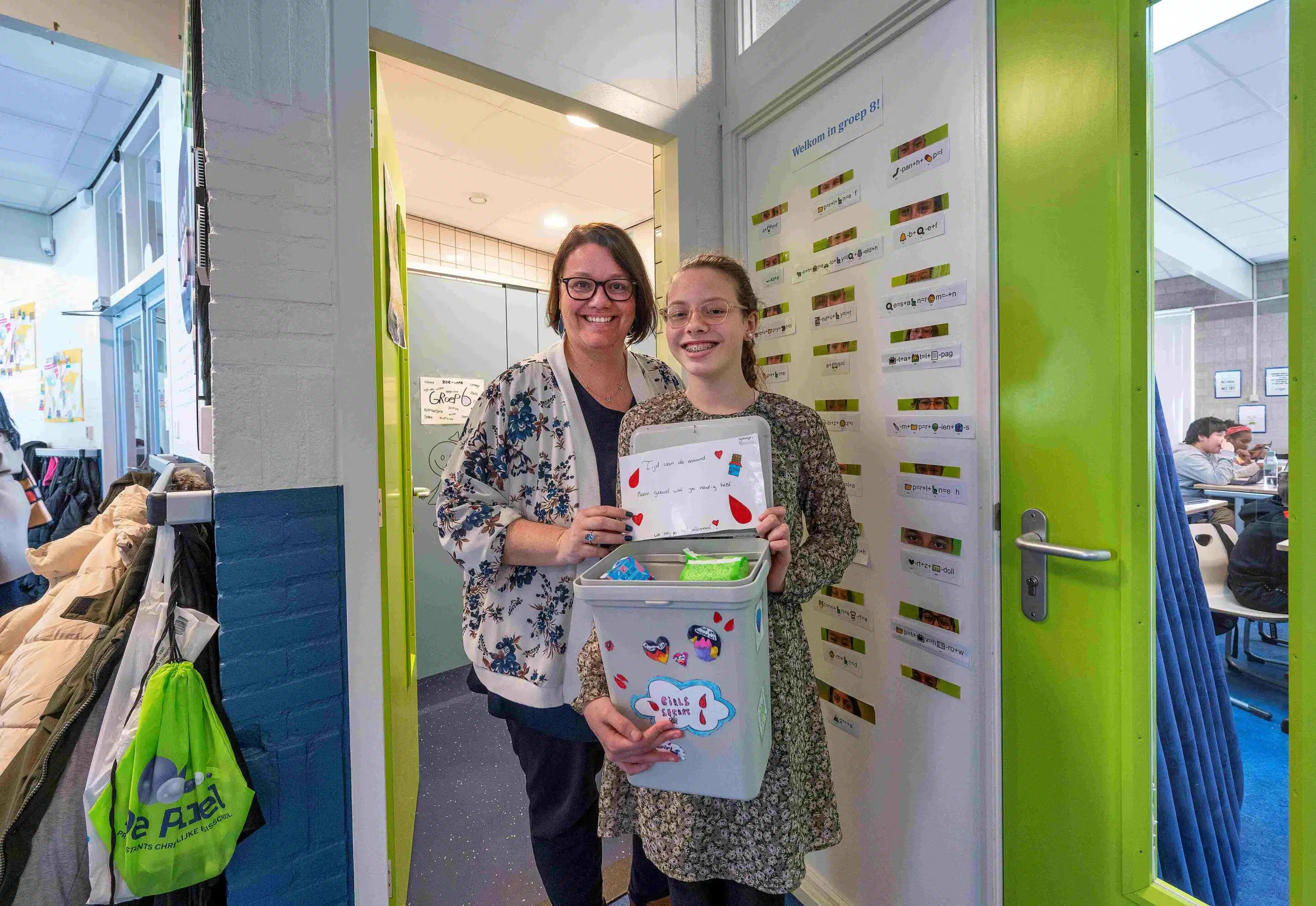 Een scholier en docent staan met de gratis menstruatieproducten op een school.