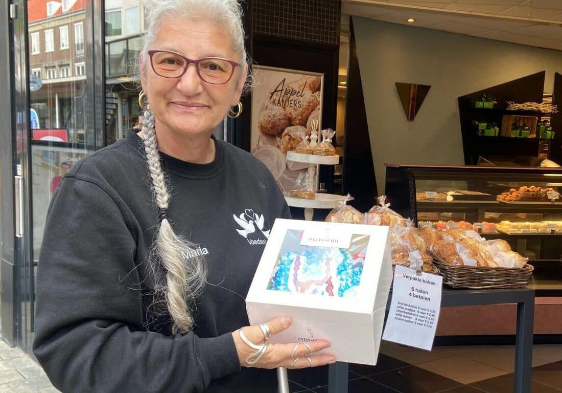 Maria van de Stichting Samen zijn we er voor elkaar staat met een verjaardagstaart in haar handen. Ze heeft deze net opgehaald bij de bakker.